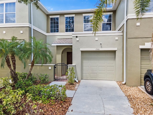 view of front of house with an attached garage, a gate, stucco siding, and driveway