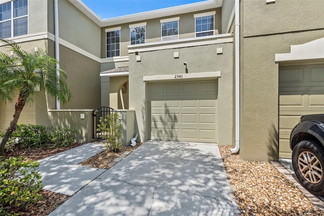 view of front of house featuring a garage, stucco siding, driveway, and a gate