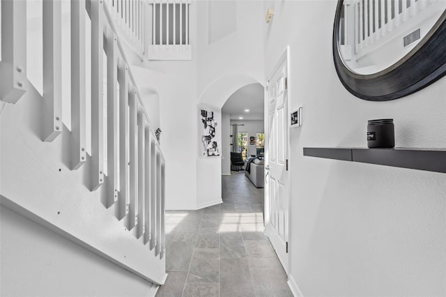entrance foyer with baseboards, a high ceiling, and arched walkways