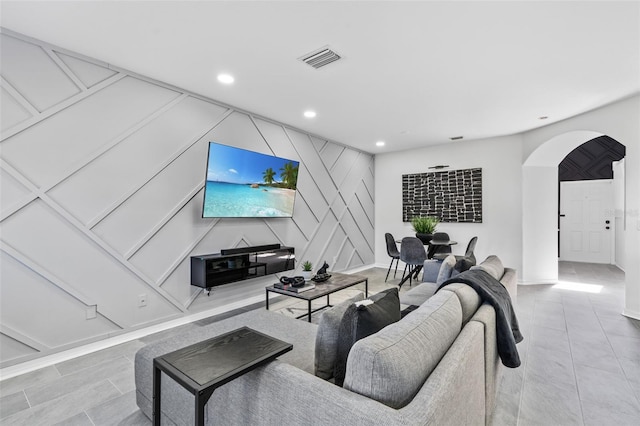 living area with tile patterned flooring, visible vents, baseboards, recessed lighting, and arched walkways