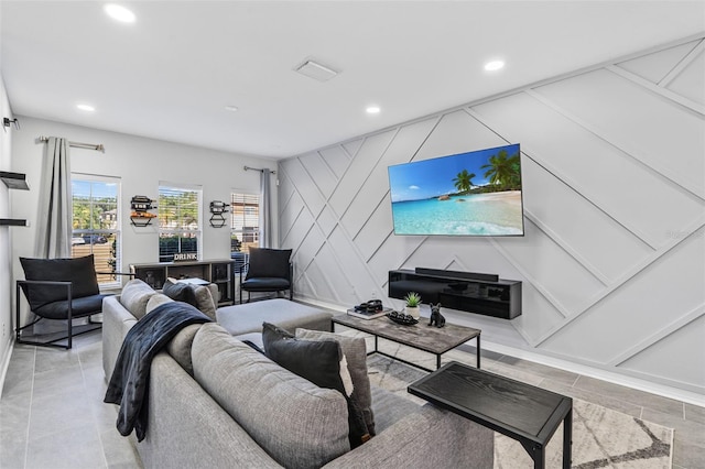 living room with baseboards, a decorative wall, recessed lighting, and visible vents
