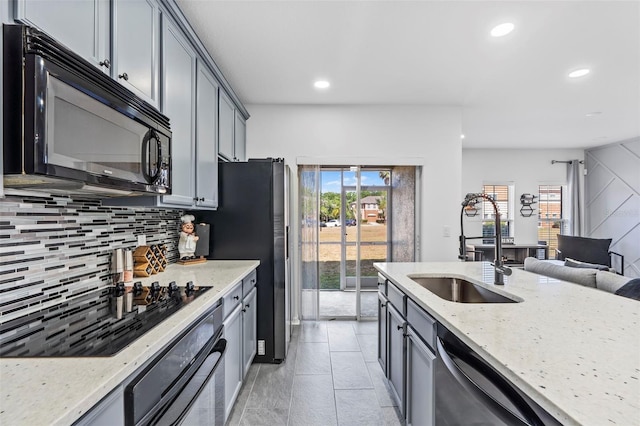 kitchen featuring light stone counters, a sink, recessed lighting, decorative backsplash, and black appliances