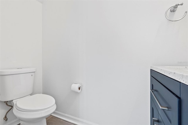 half bathroom with toilet, baseboards, and vanity