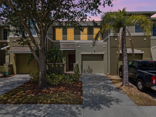 townhome / multi-family property with an attached garage, stucco siding, and concrete driveway