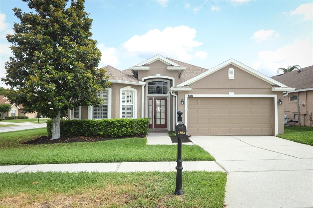 2752 Bellewater Pl, Oviedo, FL 32765 - view of front facade featuring stucco siding, a garage, driveway, and a front lawn