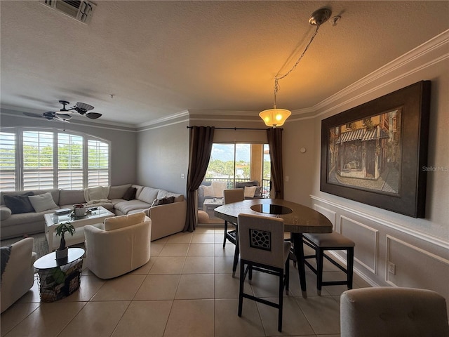 4333 Bayside Village Dr Unit 310, Tampa, FL 33615 - dining room featuring crown molding, light tile patterned floors, a textured ceiling, wainscoting, and a decorative wall