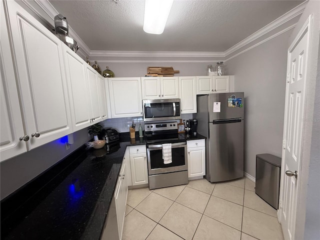 4333 Bayside Village Dr Unit 310, Tampa, FL 33615 - kitchen with appliances with stainless steel finishes, dark countertops, crown molding, white cabinets, and light tile patterned floors