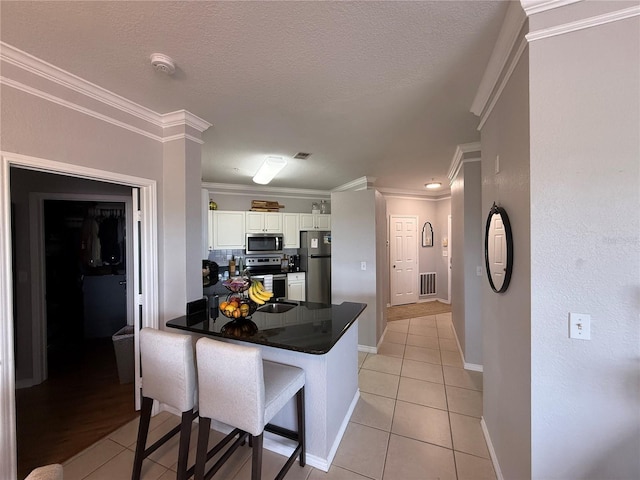 4333 Bayside Village Dr Unit 310, Tampa, FL 33615 - kitchen with appliances with stainless steel finishes, dark countertops, white cabinetry, a kitchen breakfast bar, and a peninsula