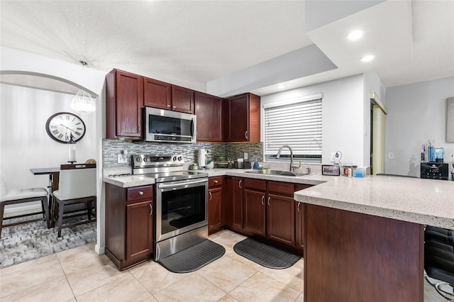 5113 Sage Way, Kissimmee, FL 34758 - kitchen with appliances with stainless steel finishes, a sink, a peninsula, light tile patterned flooring, and tasteful backsplash