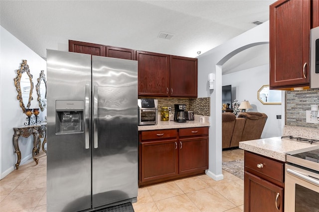 5113 Sage Way, Kissimmee, FL 34758 - kitchen with stainless steel appliances, tasteful backsplash, arched walkways, and light tile patterned flooring