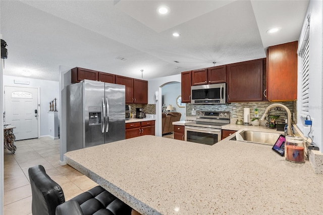 5113 Sage Way, Kissimmee, FL 34758 - kitchen featuring appliances with stainless steel finishes, a sink, a peninsula, light countertops, and arched walkways
