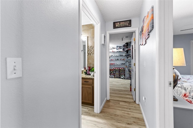 5113 Sage Way, Kissimmee, FL 34758 - hall featuring light wood-type flooring, a textured ceiling, and baseboards