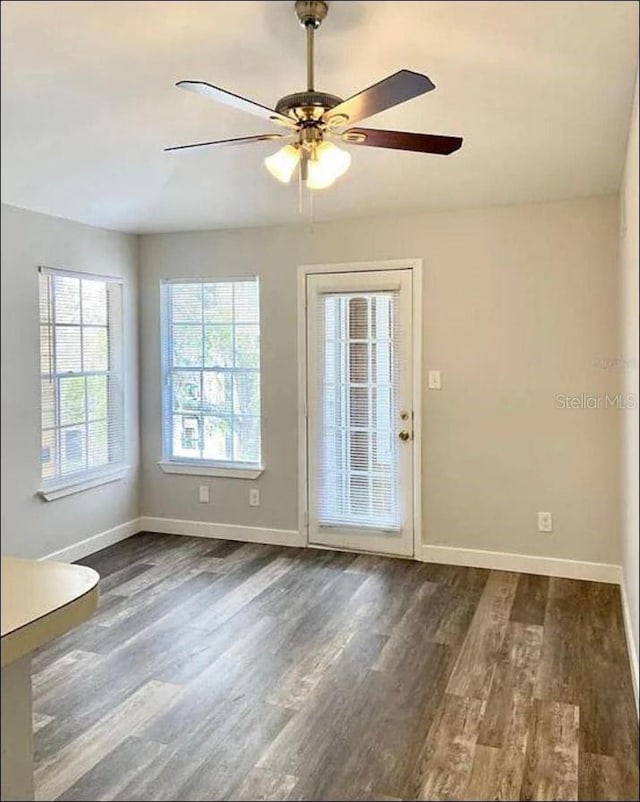 doorway to outside featuring baseboards, a ceiling fan, and dark wood-style flooring