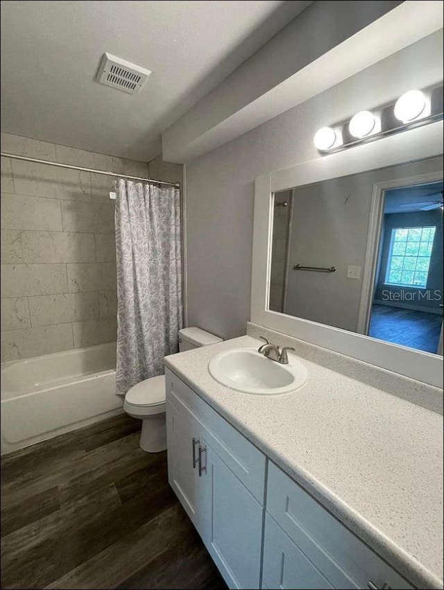 full bathroom with visible vents, vanity, wood finished floors, toilet, and shower / bath combo