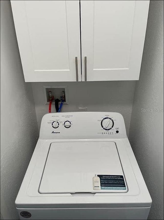 laundry room featuring cabinet space, washer / clothes dryer, and a textured wall