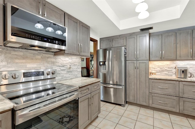kitchen with stainless steel appliances, visible vents, decorative backsplash, light tile patterned floors, and a raised ceiling