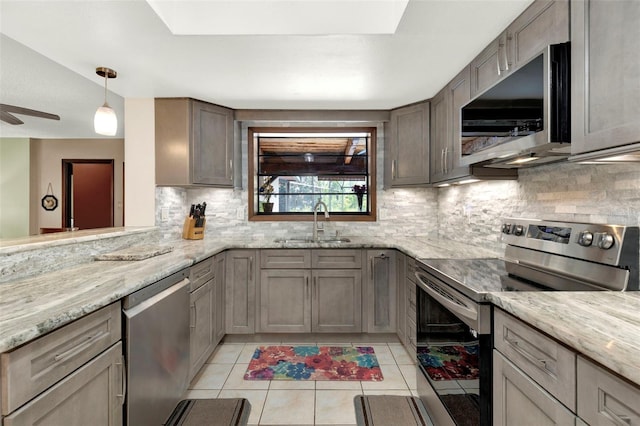 kitchen with a sink, light tile patterned flooring, decorative backsplash, light stone countertops, and appliances with stainless steel finishes