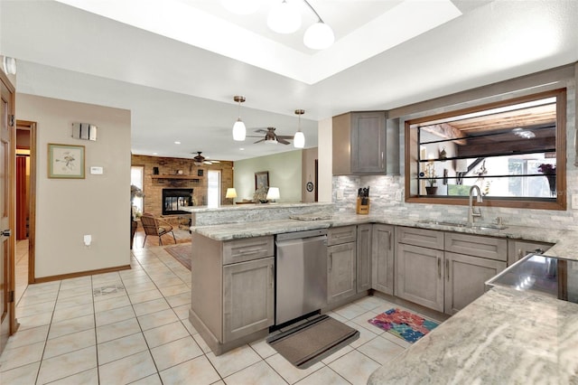 kitchen featuring a peninsula, light tile patterned floors, a sink, stainless steel dishwasher, and backsplash