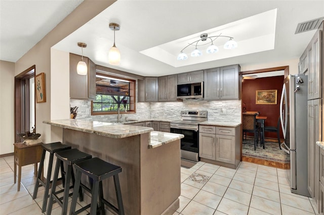 kitchen featuring light stone counters, visible vents, a peninsula, and appliances with stainless steel finishes
