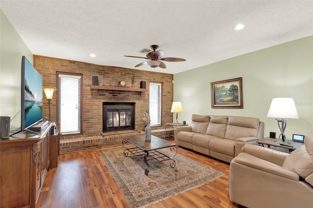 living room featuring brick wall, a textured ceiling, a ceiling fan, and wood finished floors