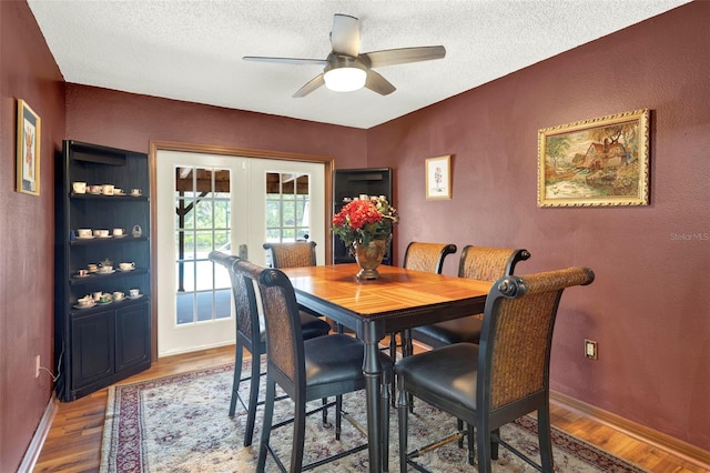 dining area featuring a textured ceiling, a ceiling fan, french doors, and wood finished floors