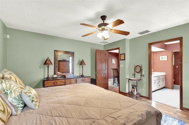 bedroom with a textured ceiling, baseboards, ceiling fan, visible vents, and wood finished floors