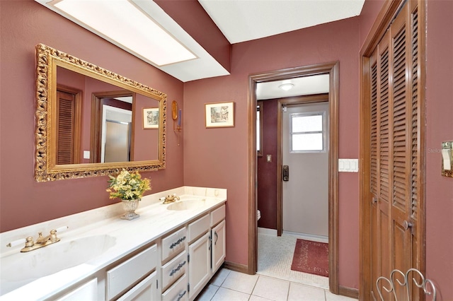 bathroom with double vanity, a closet, tile patterned flooring, and a sink