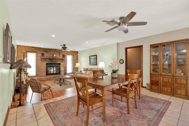 dining room with a ceiling fan, recessed lighting, a textured ceiling, light tile patterned flooring, and a fireplace