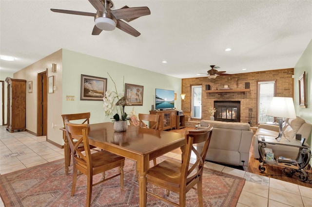 dining space featuring recessed lighting, a fireplace, ceiling fan, light tile patterned floors, and brick wall