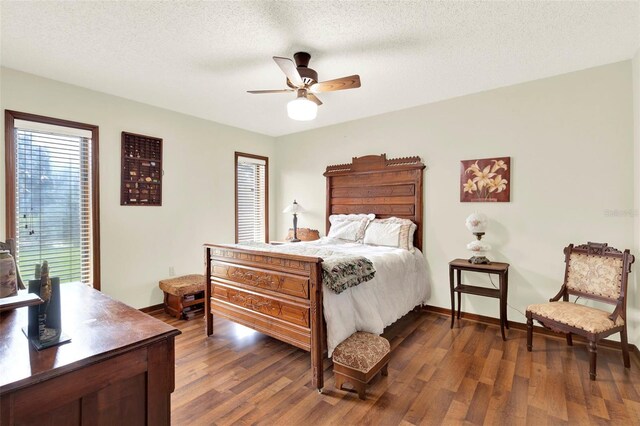 bedroom with dark wood-style flooring, a textured ceiling, baseboards, and ceiling fan