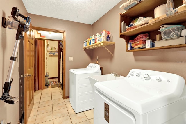 laundry area featuring laundry area, a textured ceiling, light tile patterned flooring, and washing machine and clothes dryer