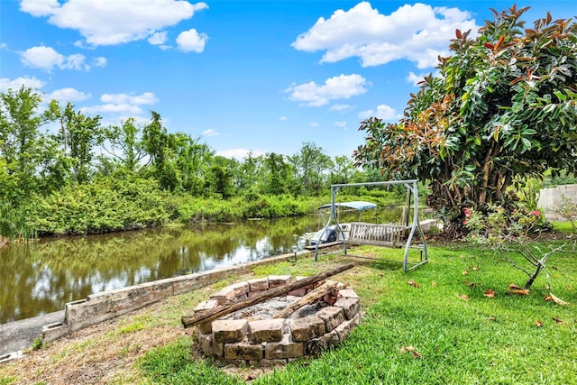 dock area with an outdoor fire pit, a water view, and a lawn