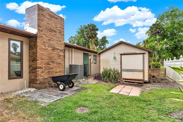 view of yard with central air condition unit, an outdoor structure, fence, and a storage unit