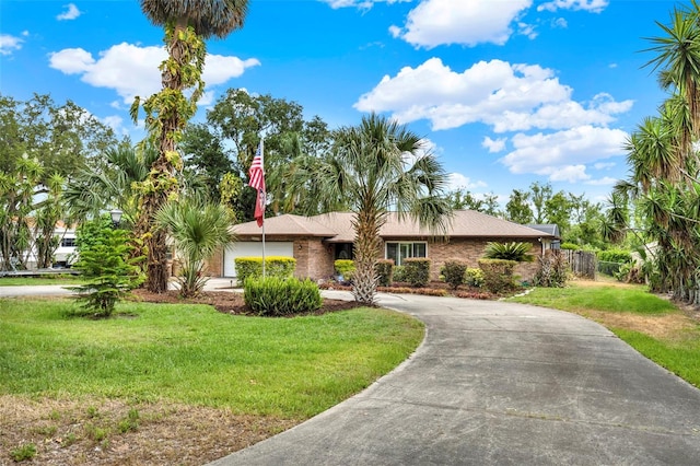 single story home featuring a front yard, a garage, fence, and curved driveway