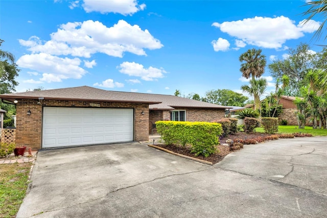 ranch-style home with concrete driveway, a shingled roof, brick siding, and a garage