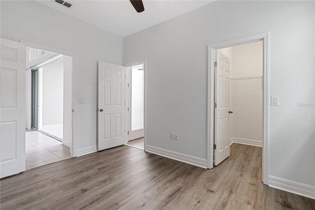 unfurnished bedroom with light wood finished floors, a closet, visible vents, and a walk in closet