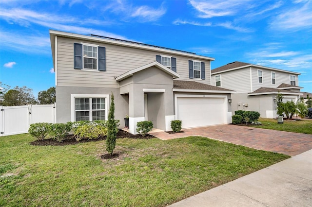 traditional-style home featuring a garage, fence, decorative driveway, stucco siding, and a gate