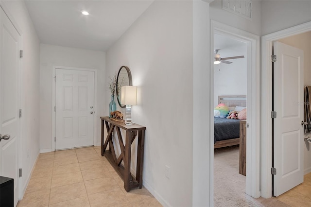 corridor featuring visible vents, baseboards, and light tile patterned floors