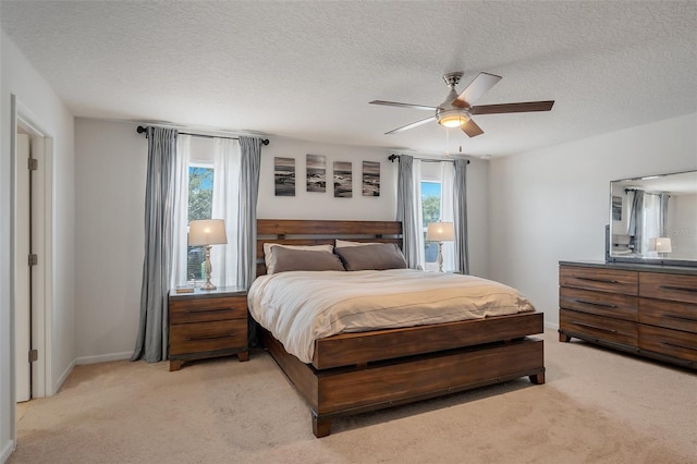 bedroom with a textured ceiling, light colored carpet, and baseboards