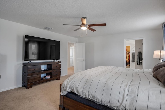 bedroom featuring ceiling fan, a textured ceiling, visible vents, light colored carpet, and baseboards