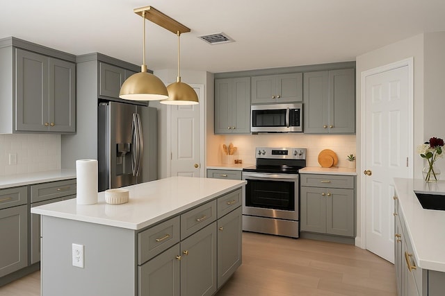 kitchen with light wood-type flooring, stainless steel appliances, gray cabinetry, and decorative backsplash