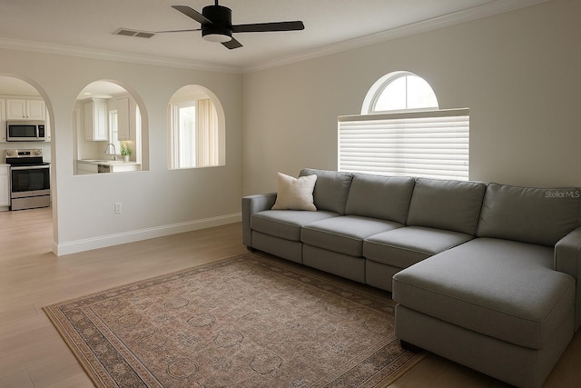 living room with light wood-type flooring, crown molding, a ceiling fan, and visible vents