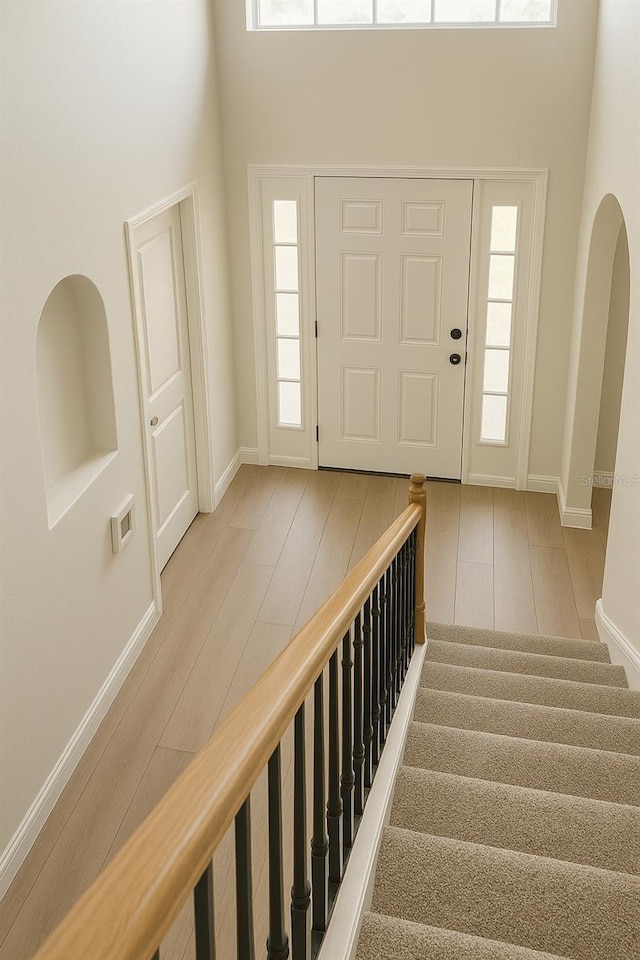 entrance foyer with a towering ceiling, stairs, baseboards, and wood finished floors