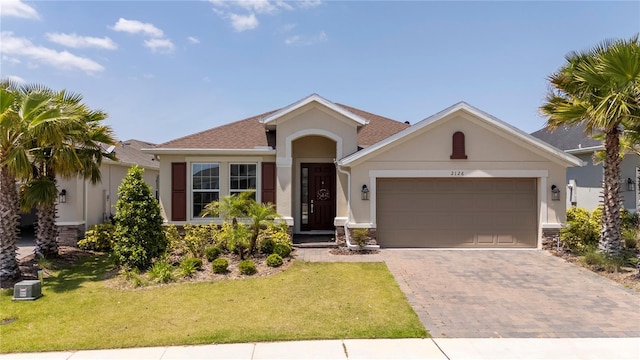 view of front of home featuring a garage, stucco siding, decorative driveway, and a front yard