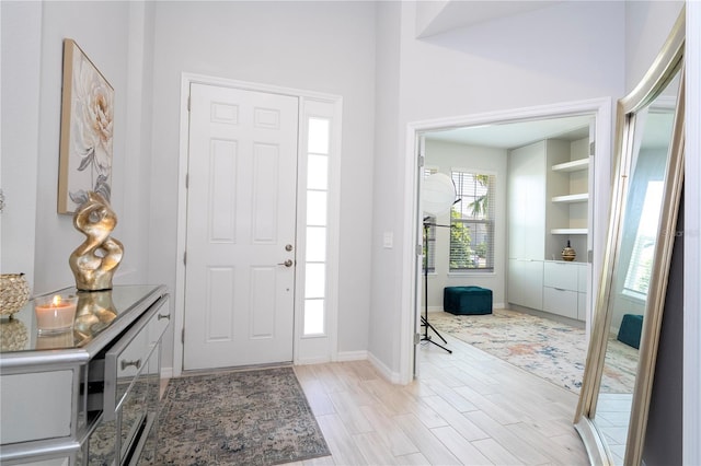 foyer entrance with baseboards and light wood-style flooring