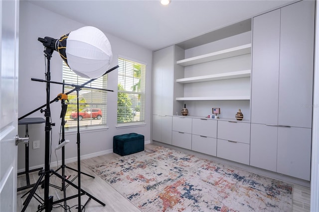 interior space featuring built in shelves, baseboards, and light wood-style flooring