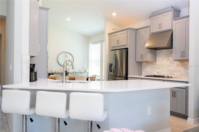 kitchen featuring under cabinet range hood, a sink, appliances with stainless steel finishes, and gray cabinets
