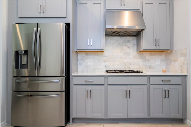 kitchen featuring stainless steel fridge, gas cooktop, exhaust hood, and gray cabinetry