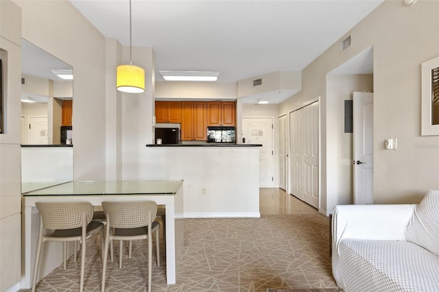 7395 Universal Blvd Unit 203, Orlando, FL 32819 - kitchen with dark countertops, visible vents, brown cabinets, and refrigerator