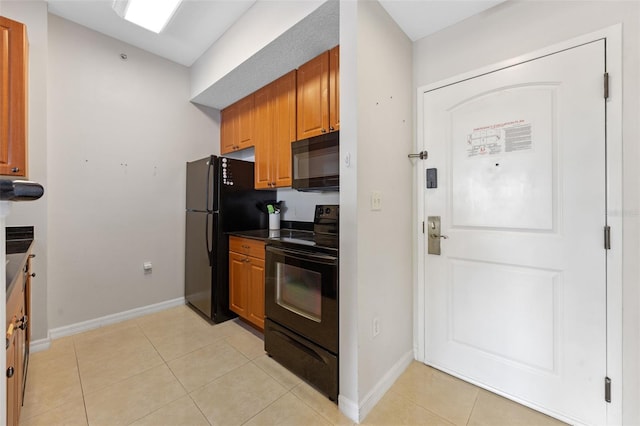 7395 Universal Blvd Unit 203, Orlando, FL 32819 - kitchen with dark countertops, brown cabinetry, baseboards, black appliances, and light tile patterned flooring